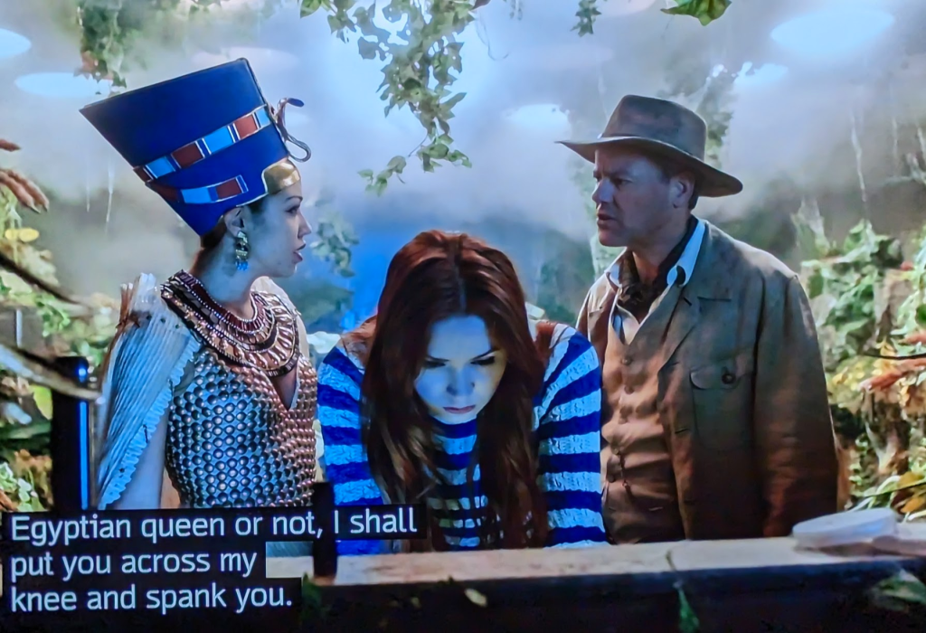 Amy Pond leans over to use a console while an early-1900s adventurer stares at Queen Nefertiti and says to her: "Egyptian queen or not, I shall put you across my knee and spank you."