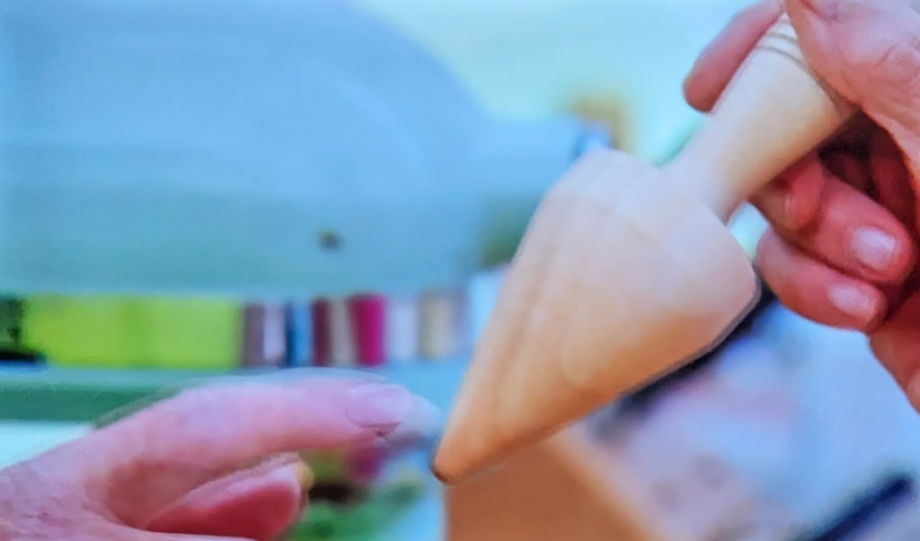 A wooden object that looks like a spinning top... or a butt plug.